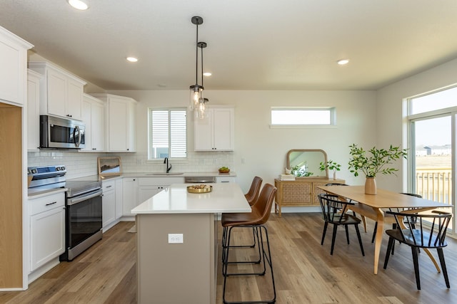 985 11th St, Waukee, IA 50263 - kitchen featuring plenty of natural light, a center island, appliances with stainless steel finishes, and a sink