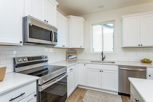 985 11th St, Waukee, IA 50263 - kitchen with a sink, stainless steel appliances, light wood finished floors, white cabinetry, and light countertops