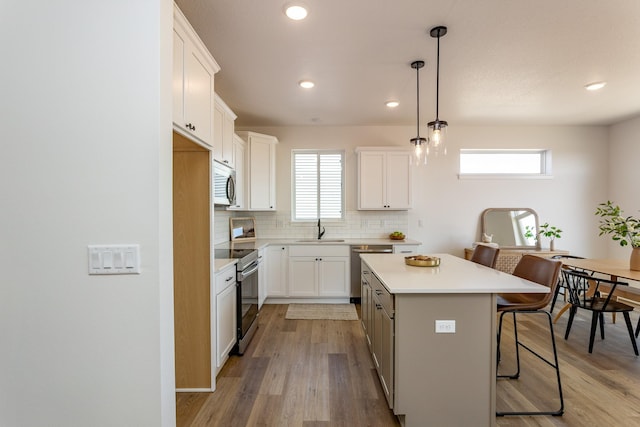 985 11th St, Waukee, IA 50263 - kitchen with a kitchen bar, a wealth of natural light, backsplash, appliances with stainless steel finishes, and a kitchen island