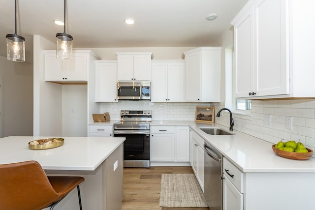 985 11th St, Waukee, IA 50263 - kitchen featuring a sink, appliances with stainless steel finishes, white cabinetry, light countertops, and light wood-style floors