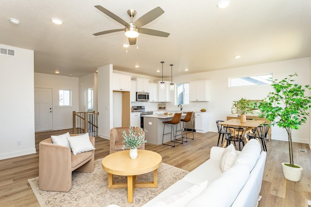 985 11th St, Waukee, IA 50263 - living room featuring ceiling fan, light wood-style flooring, visible vents, and plenty of natural light