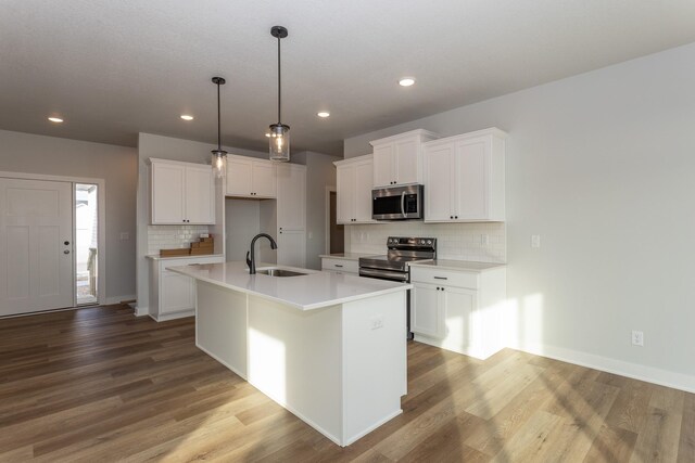 1060 Gray Ave, Waukee, IA 50263 - kitchen featuring white cabinetry, a sink, light wood-style floors, a kitchen island with sink, and appliances with stainless steel finishes