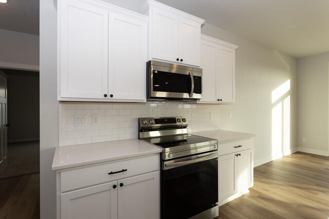 1060 Gray Ave, Waukee, IA 50263 - kitchen featuring backsplash, light countertops, appliances with stainless steel finishes, and wood finished floors