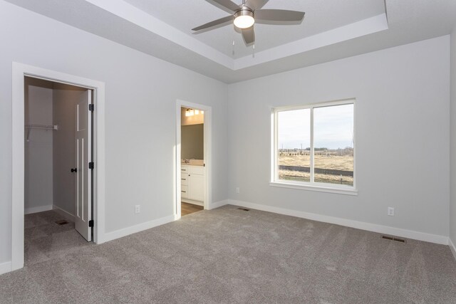 1060 Gray Ave, Waukee, IA 50263 - unfurnished bedroom featuring a spacious closet, carpet flooring, baseboards, a raised ceiling, and visible vents