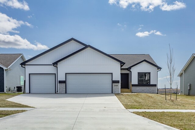 1060 Gray Ave, Waukee, IA 50263 - view of front of house with stone siding, driveway, a front lawn, and an attached garage