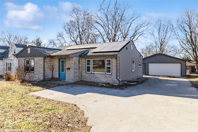 ranch-style home featuring solar panels, a garage, and an outbuilding