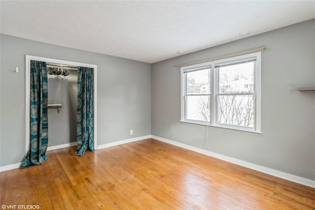 empty room with hardwood / wood-style floors and a textured ceiling