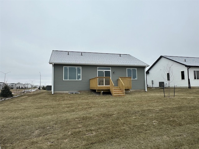 rear view of property with a shingled roof, a yard, a wooden deck, and central air condition unit