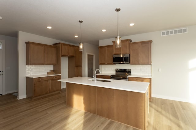 kitchen featuring stainless steel appliances, brown cabinets, visible vents, and a sink