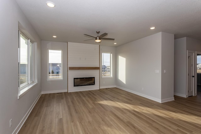 unfurnished living room with a fireplace, recessed lighting, ceiling fan, wood finished floors, and baseboards