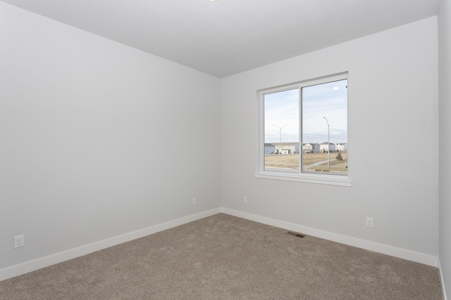 carpeted spare room featuring visible vents and baseboards