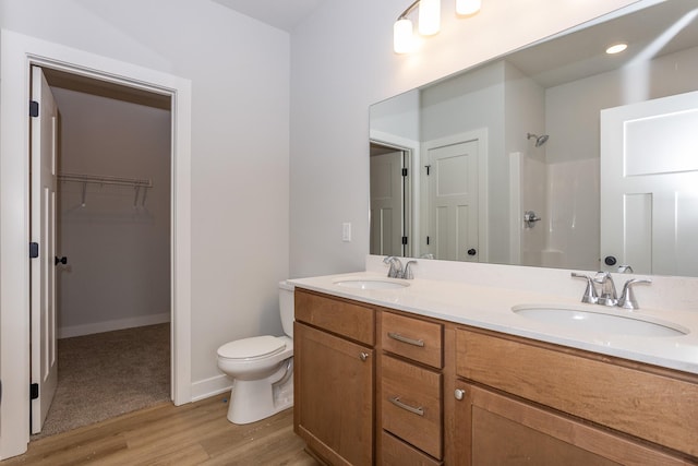 full bathroom featuring wood finished floors, walk in shower, a sink, and toilet