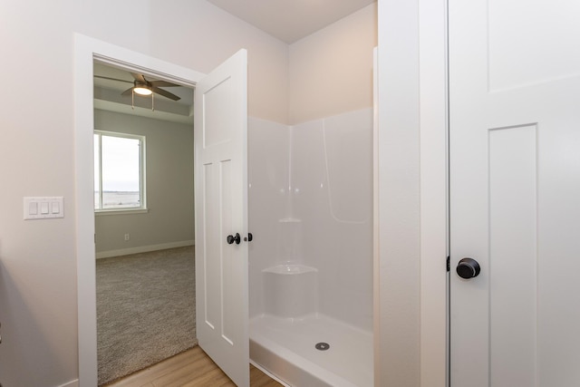 full bathroom with baseboards, a walk in shower, and wood finished floors