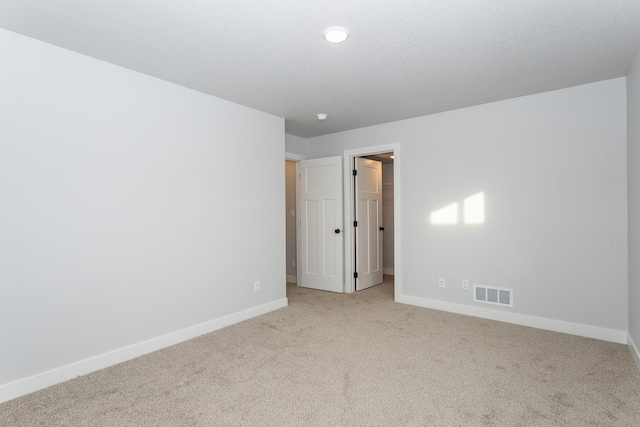 carpeted spare room featuring baseboards, visible vents, and a textured ceiling