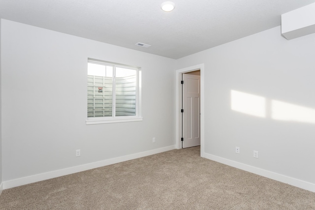 carpeted spare room featuring baseboards and visible vents