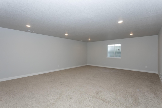 carpeted spare room with a textured ceiling, baseboards, visible vents, and recessed lighting