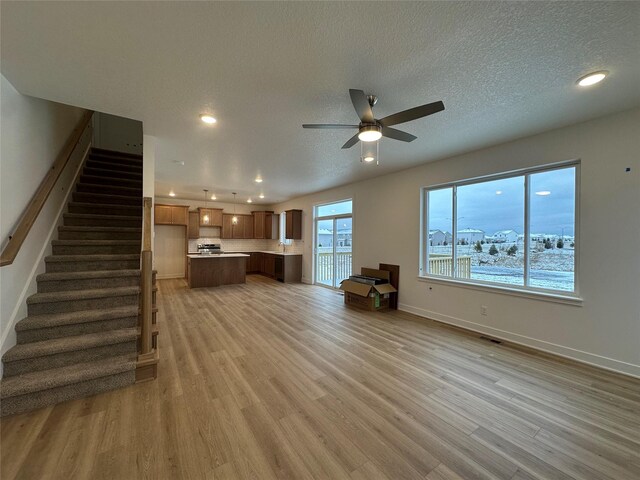 unfurnished living room with ceiling fan, light hardwood / wood-style floors, and a textured ceiling