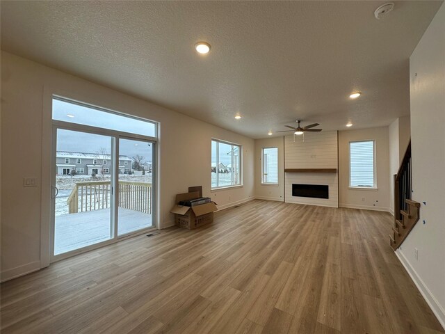 unfurnished living room with a fireplace, a textured ceiling, hardwood / wood-style flooring, and ceiling fan