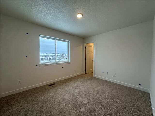 empty room with a textured ceiling and carpet floors