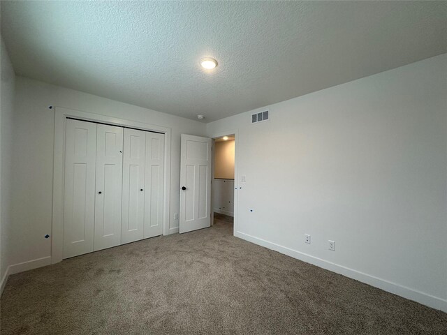 unfurnished bedroom featuring carpet, a textured ceiling, and a closet