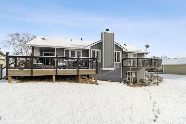 snow covered rear of property with a wooden deck