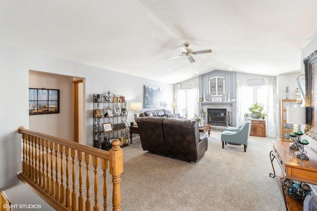 living room with carpet flooring, ceiling fan, lofted ceiling, and a brick fireplace