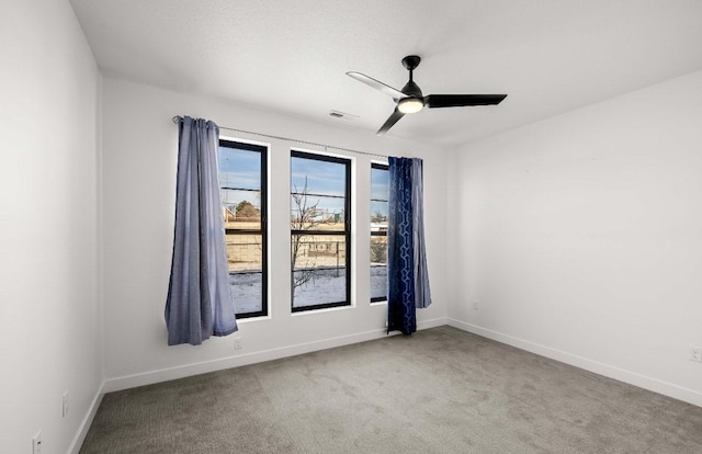 spare room with carpet floors, visible vents, baseboards, and a ceiling fan