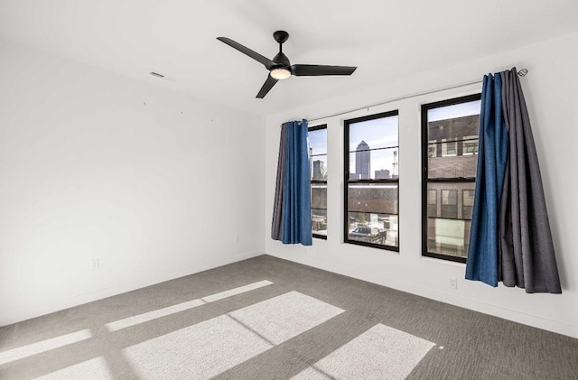 carpeted empty room featuring a ceiling fan, visible vents, and baseboards