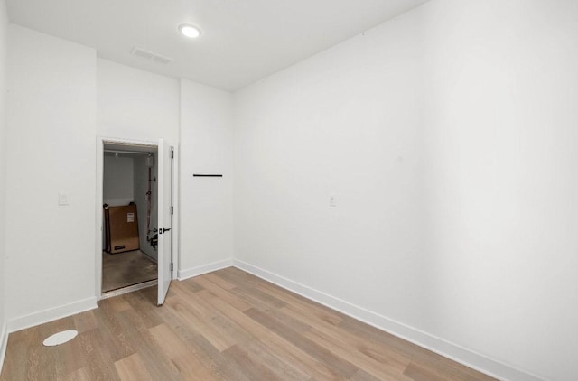 unfurnished room with light wood finished floors, visible vents, and baseboards