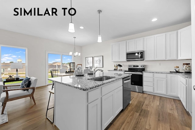 kitchen featuring white cabinets, stainless steel appliances, a center island with sink, and sink