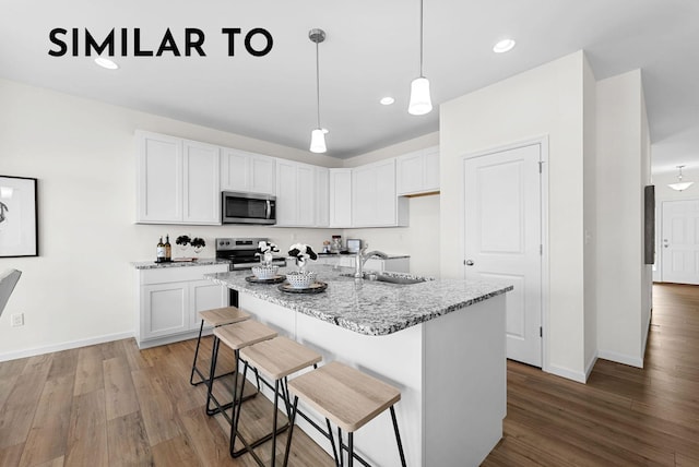 kitchen with white cabinetry, sink, light stone counters, and appliances with stainless steel finishes