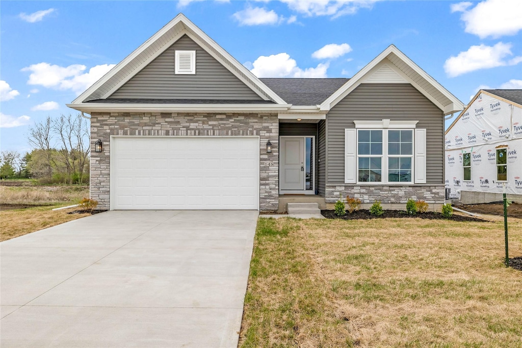 single story home with a shingled roof, concrete driveway, stone siding, a front yard, and a garage