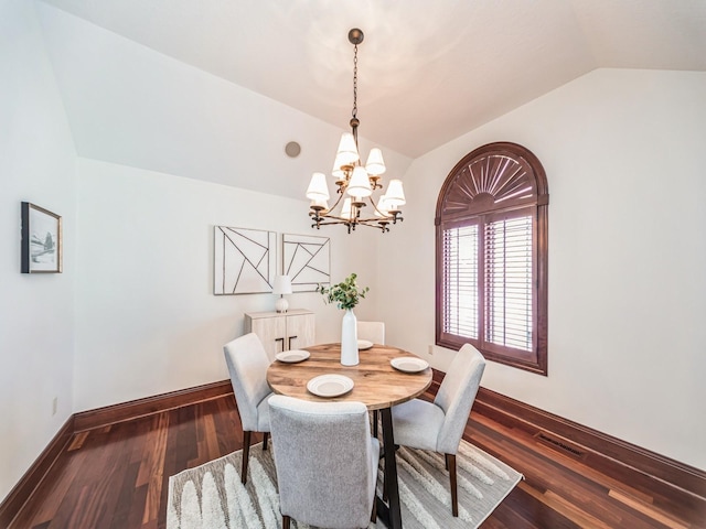 dining area with dark hardwood / wood-style flooring, an inviting chandelier, and lofted ceiling