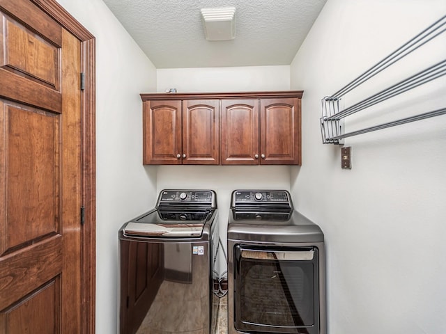 laundry room featuring cabinets, washer and dryer, and a textured ceiling