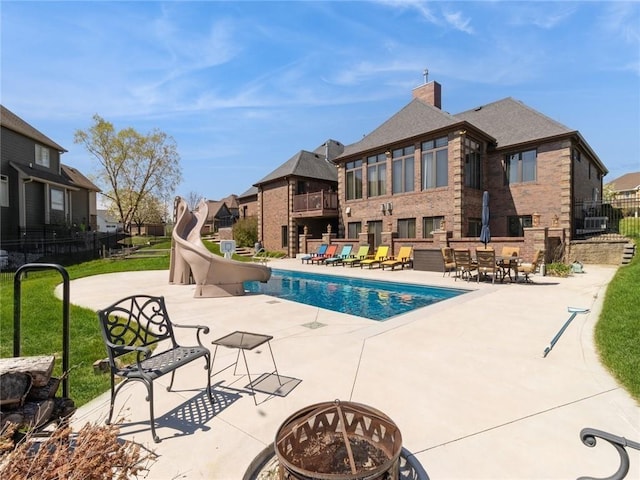 view of pool with a patio, an outdoor fire pit, and a water slide