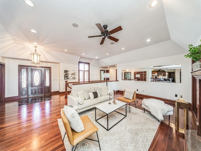 living room featuring a high end fireplace, hardwood / wood-style floors, ceiling fan with notable chandelier, and vaulted ceiling