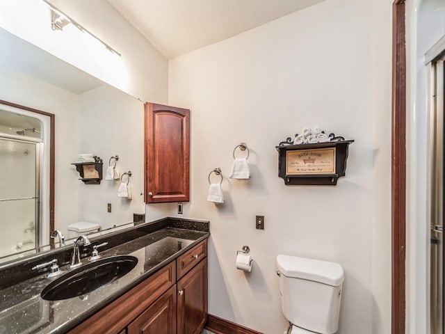 bathroom with vanity, toilet, and a shower with shower door