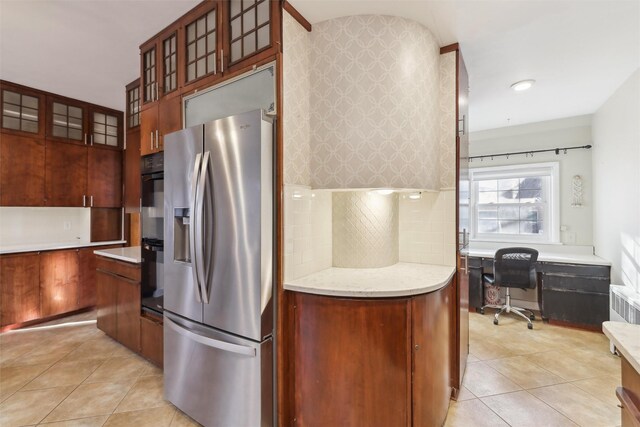 kitchen with decorative backsplash, stainless steel fridge, built in desk, and light tile patterned flooring