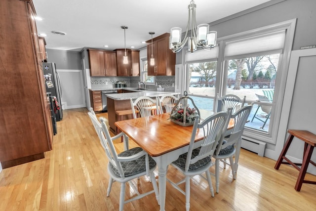 dining area featuring baseboard heating, a wealth of natural light, a notable chandelier, and light wood-type flooring