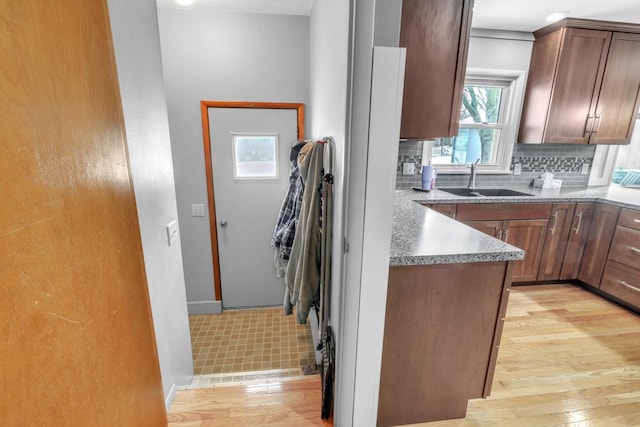 kitchen featuring light wood-type flooring, sink, and tasteful backsplash