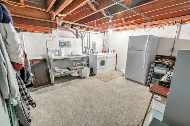 basement featuring washer and clothes dryer, white fridge, and sink