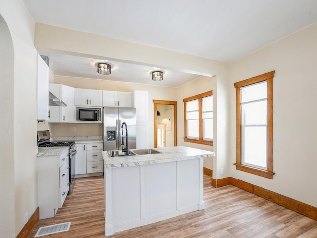 kitchen with stainless steel appliances, sink, a center island with sink, light hardwood / wood-style flooring, and white cabinets