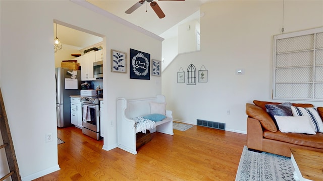 living room featuring ceiling fan, lofted ceiling, and light wood-type flooring