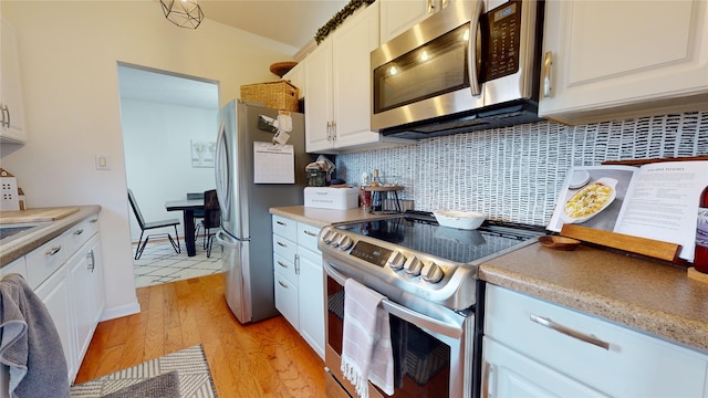 kitchen featuring decorative backsplash, white cabinetry, light hardwood / wood-style flooring, and appliances with stainless steel finishes