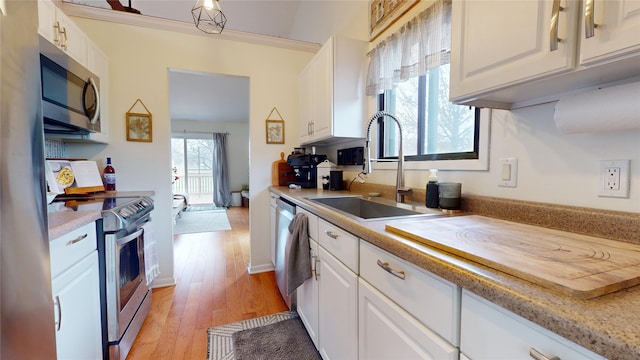 kitchen featuring stainless steel appliances, crown molding, sink, white cabinets, and light hardwood / wood-style floors