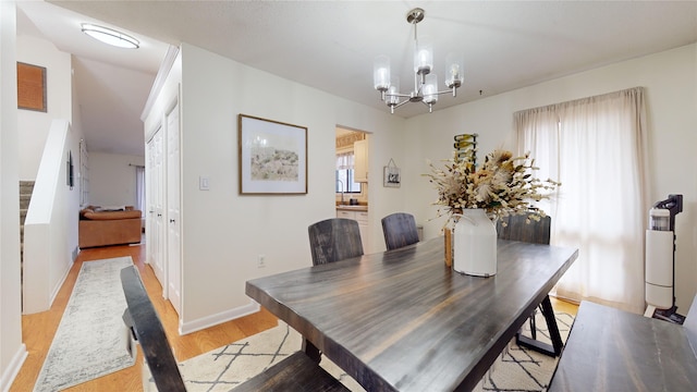 dining area with light wood-type flooring and an inviting chandelier