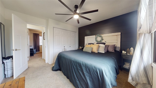 carpeted bedroom featuring a closet, ceiling fan, and wood walls