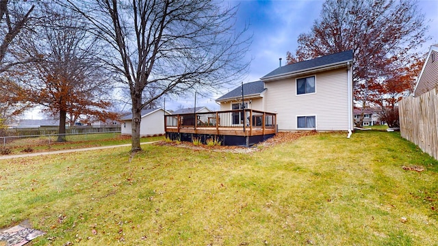 rear view of property featuring fence, a deck, and a lawn