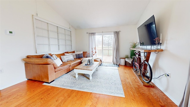 living room featuring lofted ceiling, wood finished floors, and baseboards