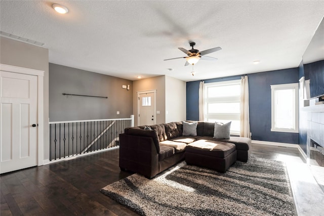 living room with ceiling fan, dark hardwood / wood-style flooring, and a textured ceiling